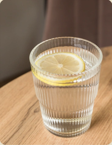 Ein Glas warmes Wasser mit einer Zitronenscheibe auf einem Holztisch