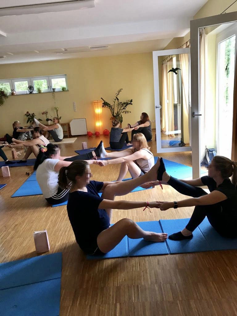 Eine Yogagruppe übt gemeinsam im Kursraum