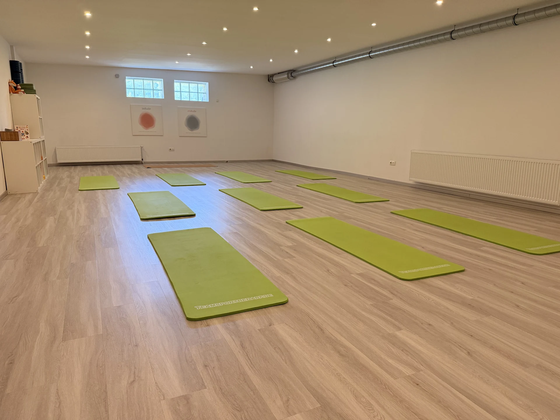Großzügiger Kursraum mit grünen Yogamatten und hellem Holzboden in der Physiotherapie Meurer in Bad Camberg