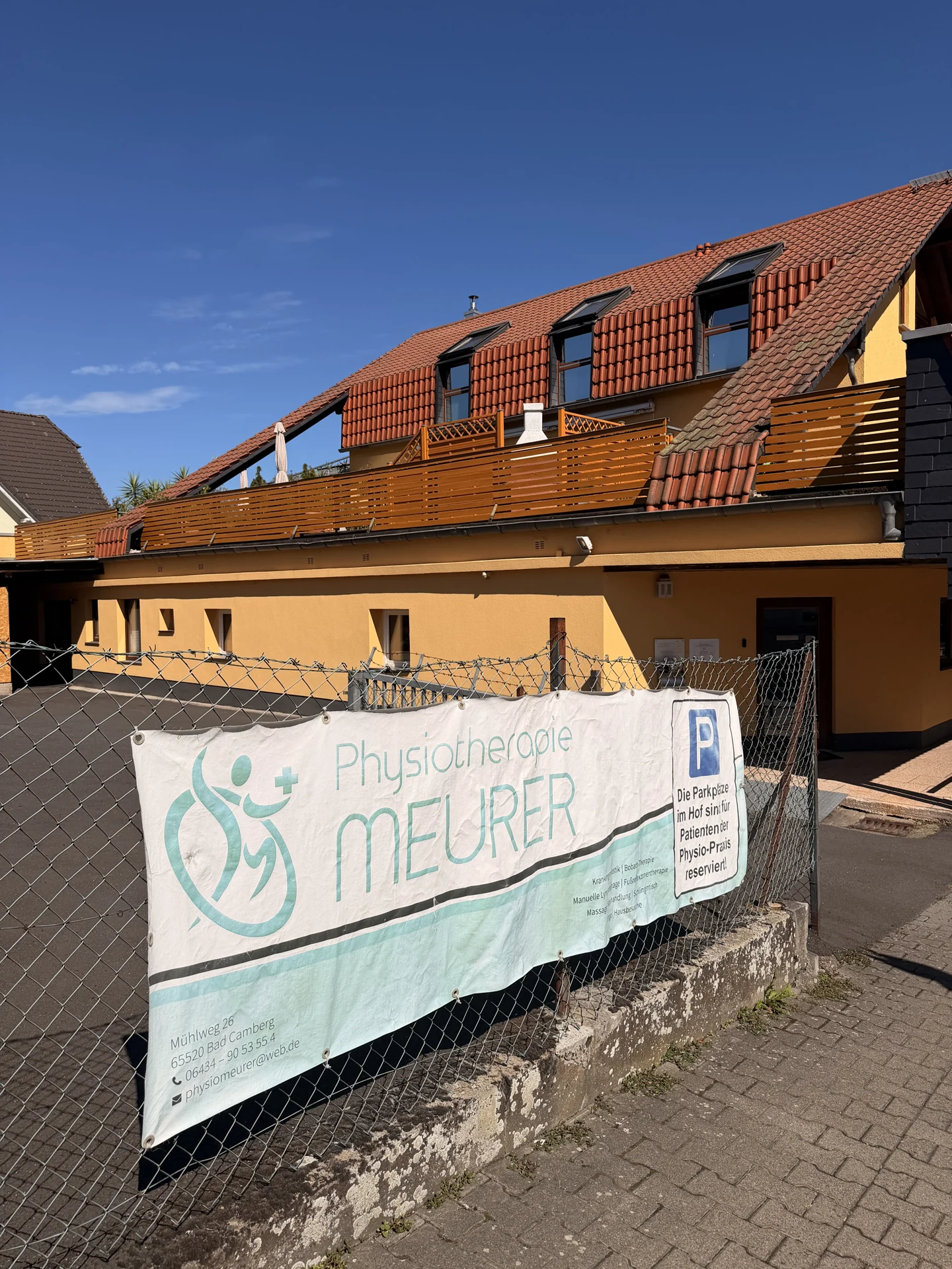 Außenansicht der Physiotherapie Meurer in Bad Camberg mit Praxisschild am Zaun