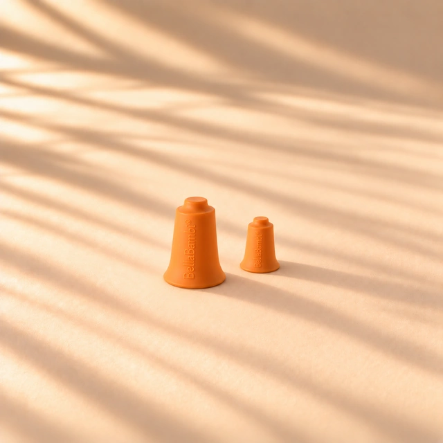Zwei orangefarbene BellaBambi-Cups in unterschiedlicher Größe im warmen Sonnenlicht