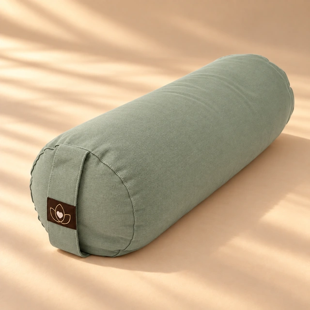 Salbeigrünes rundes Yoga-Bolster im warmen Sonnenlicht