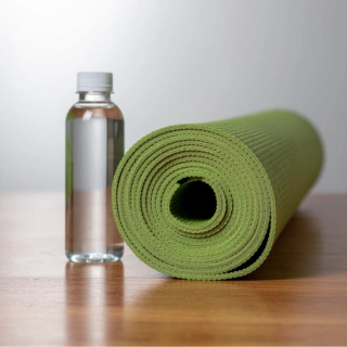Gerollte grüne Yogamatte und Wasserflasche für die erste Yogastunde