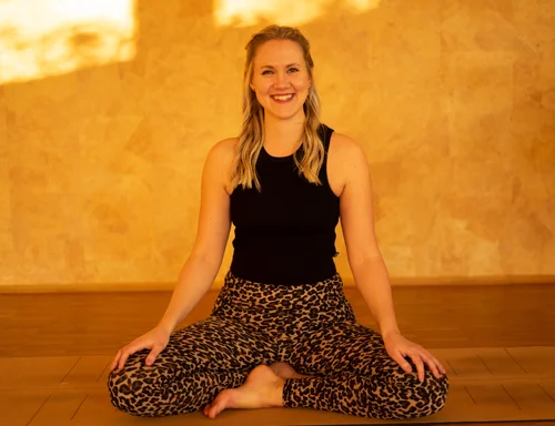 Yogalehrerin Lisa Becker sitzt lächelnd im Yogastudio